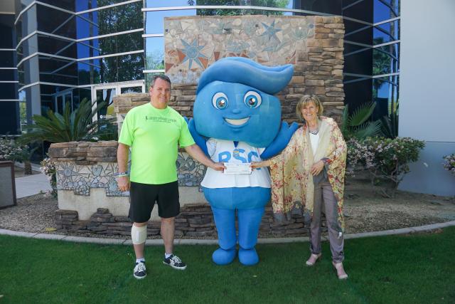 photo of Run Your Race coordinator handing off fundraising check to President Smith and mascot Splash