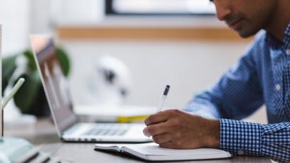 Man taking notes by laptop