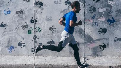 Man running past a wall covered in handprints