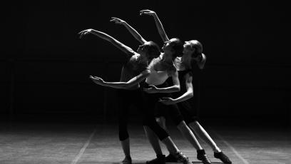 Three ballerinas dancing in a black and white photo
