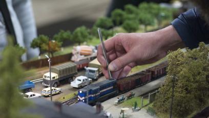 A hand works on a model train set