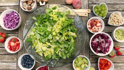 A salad surrounded by bowls of fruit and chopped vegetables