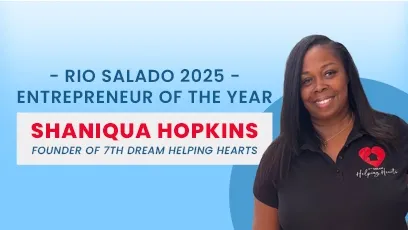 Shaniqua Hopkins, founder of 7th Dream Helping Hearts, stands smiling in front of a blue background. She wears a black polo shirt with a red heart logo on the left side. Text beside her reads: “Rio Salado 2025 Entrepreneur of the Year – Shaniqua Hopkins, Founder of 7th Dream Helping Hearts.”