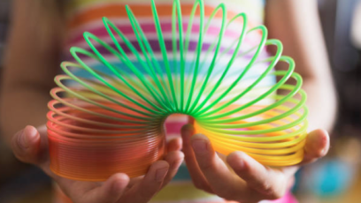 Someone holding a multi-colored Slinky toy in their hands