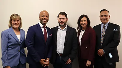 Five leaders stand side by side against a light-colored wall. From left to right: Rio Salado College President Kate Smith in a light blue suit; City of Tempe Mayor Corey Woods in a navy suit with a red tie; Arizona Sen. Ruben Gallego in a dark blazer and open-collar shirt; Tempe Chamber President & CEO Robin Arredondo-Savage in a burgundy suit; and MCCCD Chancellor Steven Gonzales in a dark suit with a patterned tie. All are smiling and facing the camera.