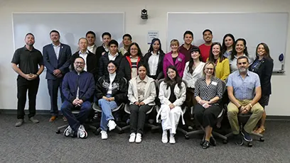 Group photo of students and instructors gathered in a classroom, standing and seated in rows.