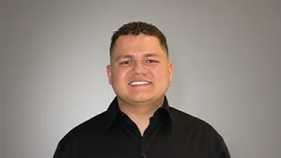 Portrait of Yeison Ramirez Mendez smiling in a black button-up shirt against a gray background.