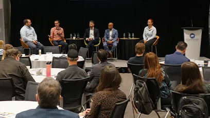 Audience members listen as panelists participate in a discussion during a professional event.