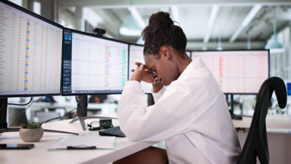 Woman stressed in an office working on computers