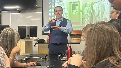 Instructor demonstrates semiconductor manufacturing concepts to a group of participants during a hands-on training session in a classroom.
