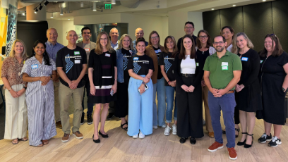 **Alt text:** Group of faculty and staff stand together smiling during a professional gathering.