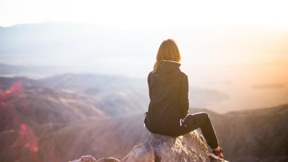 Woman sitting on a rock looking out over nature