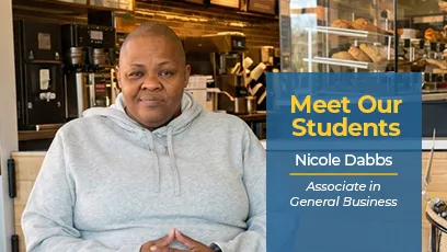 Nicole Dabbs sits inside a café wearing a gray hoodie. A blue graphic beside her reads, “Meet Our Students, Nicole Dabbs, Associate in General Business.”