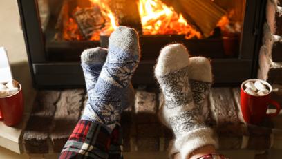 two pairs of feet wearing wooly socks in front of fire with hot cocoa