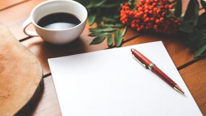 A blank journal, a cup of espresso, and red flowers