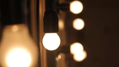 A lit lightbulb suspended in front of a vanity mirror