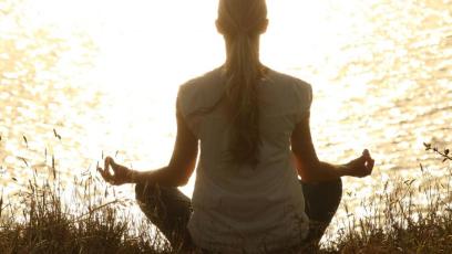 A woman meditating by a lake