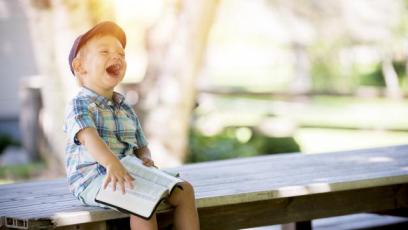 Little boy laughing while holding a book