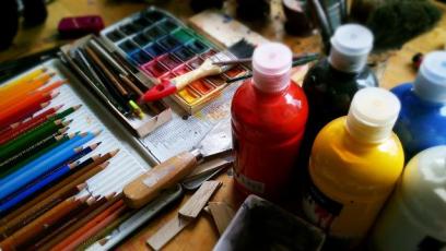 Colored pencils, paint bottles, and paintbrushes