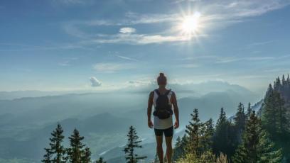 A hiker standing on a rock looking over a forest landscape