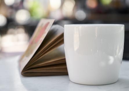 Coffee cup and journal on white table