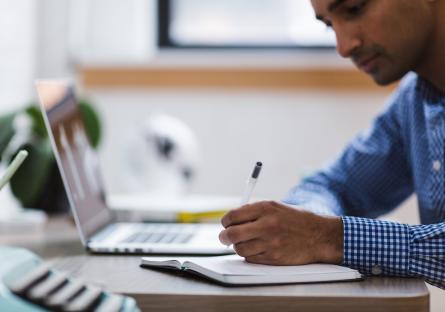 Man taking notes by laptop