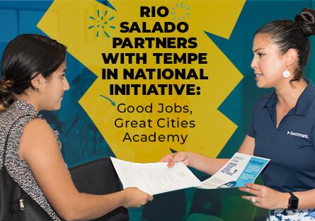 Two women sharing information at an expo booth. Text: Rio Salado Partners With Tempe in National Initiative: Good Jobs, Great Cities Academy
