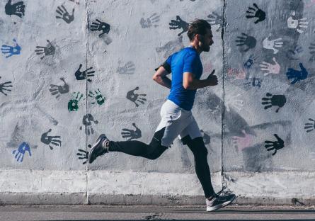 Man running past a wall covered in handprints