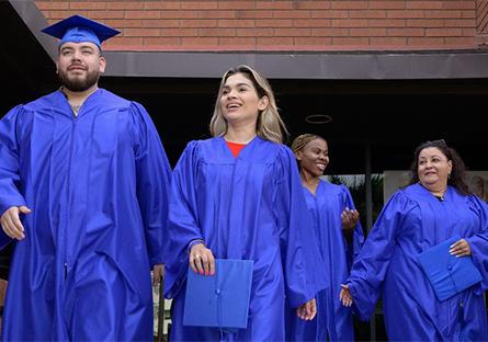 Rio Salado College graduates walking out of a building in caps and gowns