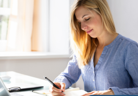 woman looking at paperwork in front of a laptop