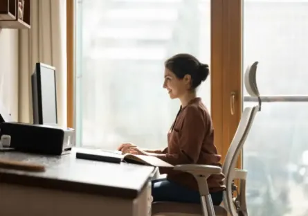 Woman sitting in ergonomic chair while working on a computer in her office