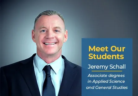 A smiling man in a suit and tie is featured against a gradient blue background. A graphic box on the right reads: Meet Our Students in bold yellow text, followed by Jeremy Schall and Associate degrees in Applied Science and General Studies in white text.