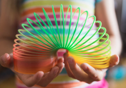 Someone holding a multi-colored Slinky toy in their hands