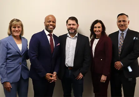 Five leaders stand side by side against a light-colored wall. From left to right: Rio Salado College President Kate Smith in a light blue suit; City of Tempe Mayor Corey Woods in a navy suit with a red tie; Arizona Sen. Ruben Gallego in a dark blazer and open-collar shirt; Tempe Chamber President & CEO Robin Arredondo-Savage in a burgundy suit; and MCCCD Chancellor Steven Gonzales in a dark suit with a patterned tie. All are smiling and facing the camera.