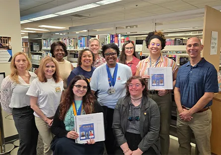 Rio Salado PTK students and staff in a library holding Braille-translated books