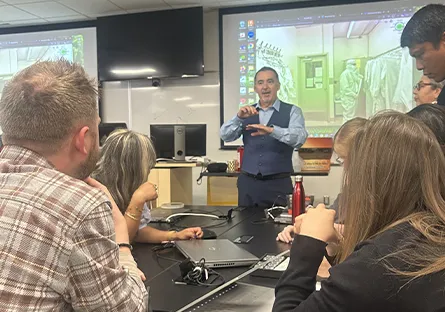 Instructor demonstrates semiconductor manufacturing concepts to a group of participants during a hands-on training session in a classroom.