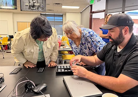 Participants examine semiconductor components during a hands-on training activity in a classroom setting.