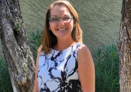 Darcy Breault smiling, standing near trees.