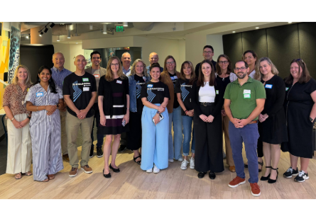 **Alt text:** Group of faculty and staff stand together smiling during a professional gathering.