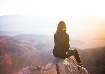 Woman sitting on a rock looking out over nature