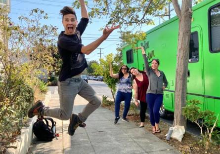 photo of three Roadtrip Nation students standing next to RV, with alum jumping in the air