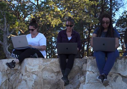 photo of three Roadtrip Nation students sitting on a stone wall while working on their laptops