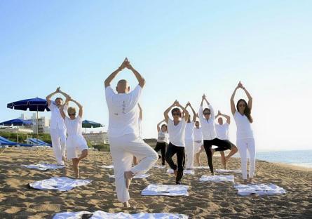A group of people practicing yoga on the beach