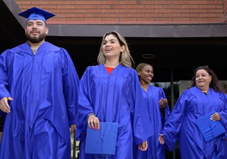 Rio Salado College graduates walking out of a building in caps and gowns