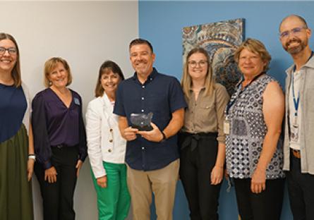 Institutional Integrity and Compliance Office staff holding the award