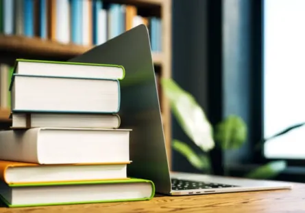 A stack of books next to an open laptop