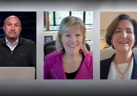 Screenshot of a virtual podcast interview featuring three speakers in separate frames: a man on the left seated at a laptop, a woman in the center wearing a pink jacket and smiling, and a woman on the right wearing a blazer and necklace, also smiling.