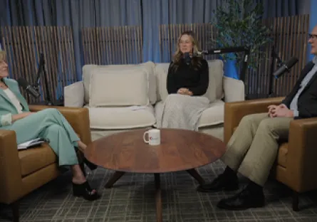 From left to right, President Kate Smith, Lindsey Crosland, and Jared Taylor are seated in armchairs around a small round table during a podcast-style conversation in a studio setting with soft lighting and plants in the background.