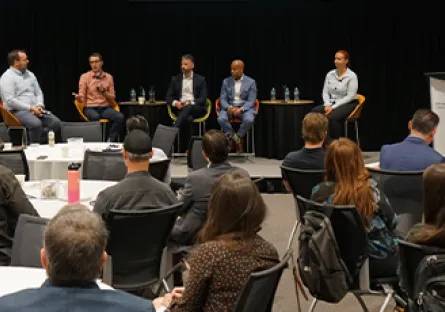 Audience members listen as panelists participate in a discussion during a professional event.