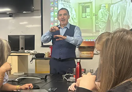 Instructor demonstrates semiconductor manufacturing concepts to a group of participants during a hands-on training session in a classroom.